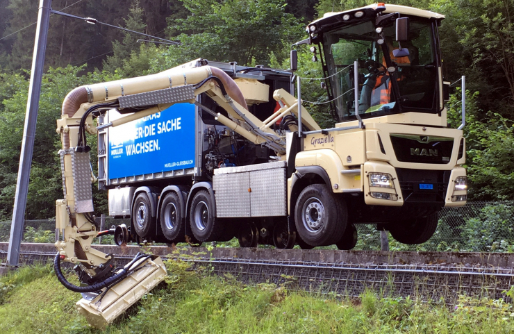 Böschungspflegemaschine mit 3teiligem Mähkran für beidseitiges Mähen/Mulchen. Aus der Drehkabine ist immer ideale Sicht auf Strasse oder Arbeit. Ein leistungsstarkes Gebläse befördert das Schnittgut in den 30 m3 fassenden Abschiebecontainer.